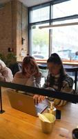 Young women in a cafe talking and using laptop video