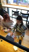 mulheres jovens em um café conversando e usando laptop video