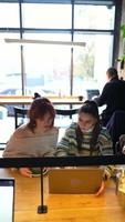 mujeres jóvenes en un café hablando y usando una computadora portátil