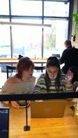 Young women in a cafe talking and using laptop video