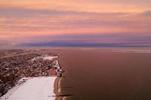 vista aérea de una playa de coney island cubierta de nieve durante el invierno al atardecer en brooklyn, nueva york foto