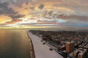 vista aérea de una playa de coney island cubierta de nieve durante el invierno al atardecer en brooklyn, nueva york foto