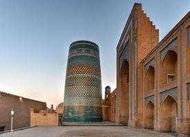 Kalta Minor Minaret and the historic architecture of Itchan Kala, walled inner town of the city of Khiva, Uzbekistan a UNESCO World Heritage Site. photo