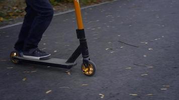 giovane ragazzo cavalcate su un' scooter a il autunno parco video