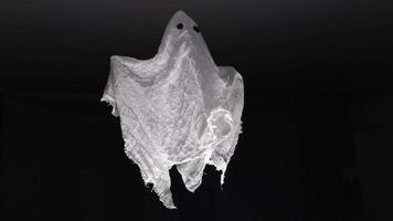 A white ghost made of fabric floating at night under the ceiling close-up video