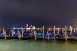 Gondola boats floating in the water at night in Venice, Italy. photo