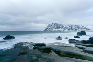 olas que fluyen sobre la playa de utakleiv, islas lofoten, noruega en el invierno. foto