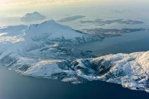 una vista aérea de las montañas cubiertas de nieve de los fiordos de noruega en el invierno. foto
