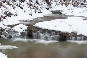 un pequeño río de bosque rocoso en invierno foto