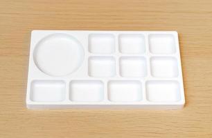 White watercolor palette. Empty watercolor tray isolated on wood background. White paint palette. photo