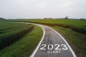 Happy new year 2023,2023 symbolizes the start of the new year. The letter start new year 2023 on the road in the nature fresh green tea farm mountain environment ecology or greenery wallpaper concept. photo