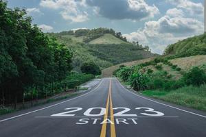 feliz año nuevo 2023,2023 simboliza el comienzo del nuevo año. la carta comienza el nuevo año 2023 en la carretera en la ruta de la naturaleza, la carretera tiene un concepto de ecología del entorno arbóreo o papel tapiz verde. foto