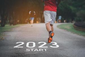 Sport man running at park garden. Start into the new year 2023. Start up of runner woman running on nature race track go to Goal of Success. People running as part of Number 2023. Sport health care. photo