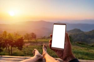 Young man traveler relaxing and using a mobile phone while traveling for summer vacation at the mountain photo