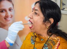 delhi, india - 19 de noviembre de 2022 - primer plano de una dentista que hace un chequeo dental de rutina al paciente, paciente acostado en una silla en el chequeo anual de salud, dentista que hace un chequeo dental al paciente foto