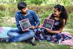 Indian couple posing for maternity baby shoot. The couple is posing in a lawn with green grass and the woman is falunting her baby bump in Lodhi Garden in New Delhi, India photo