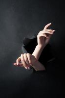 Female hands, on a black, torn background. photo