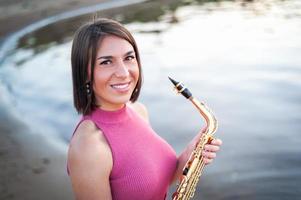 Woman playing the saxophone at sunset. photo