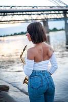 Woman playing the saxophone at sunset. photo