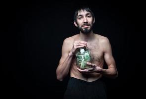 Young man with money bottle on black background photo