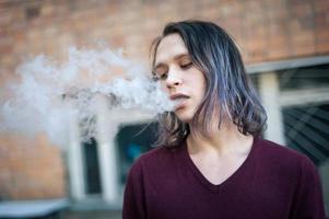 Portrait of a young man in the smoke of cigarettes photo