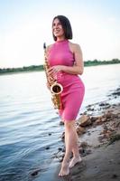 Woman playing the saxophone at sunset. photo
