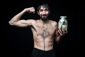 Young man with money bottle on black background photo