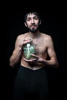 Young man with money bottle on black background photo