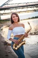 Woman playing the saxophone at sunset photo