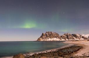 aurora boreal sobre el mar en la playa de utakleiv, islas lofoten, noruega en el invierno. foto