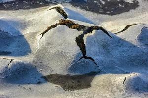 roca que se agrieta a través del hielo en boosen en las islas lofoten, noruega en el invierno. foto