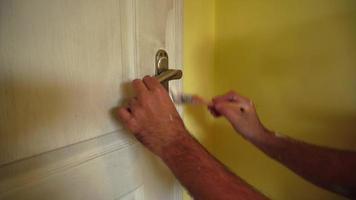 el hombre pinta la puerta de la habitación de color blanco con un pincel video