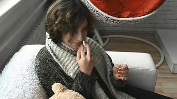 una mujer enferma con suéter goteando medicina en la nariz en casa video