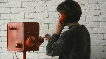 een vrouw met kort haar- wijzerplaten in retro rood telefoon video