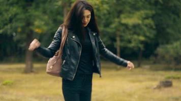 Cheerful brunette in black with backback promenades à l'extérieur sur une frontière video