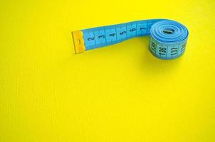 Measuring tape with copy space for text. Blue measuring tape on bright yellow background. photo