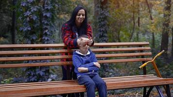 beautiful brunette mom sneak up to her little toddler son from behind at warm autumn day video