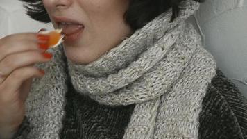 Sick young girl in sweater eats tangerine in bed at home video