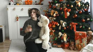 woman with short hair is photographed near the Christmas tree at home video