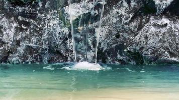 artificial waterfall on gray rocks falls into bare water in 4k video