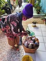 Jepara, Indonesia in July 2022. A grandmother selling herbal medicine is preparing a customer's order. photo