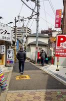 Osaka, Japan on April 10, 2019. Two Asian men walking down an alley in a village in Osaka in the transition from spring to summer, photo