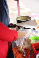 An old Indonesian woman is preparing vegetable  dishes for customers. photo