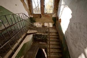 Stairs in an abandoned house, a destroyed industrial building, a house with broken windows. photo