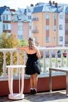The girl stands on the terrace with her shoulders turned to the photographer, dress and socks, new style. photo