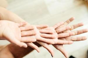 cuatro manos colocadas una encima de la otra con las palmas hacia arriba, unidad de padres e hijos. foto