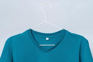 Worn blue t-shirt hanging on a hanger against gray background photo