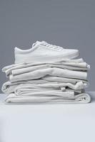 Stack of white clothes and stylish trainers photo