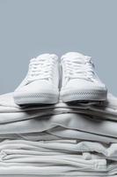 Stack of white clothes and stylish trainers photo