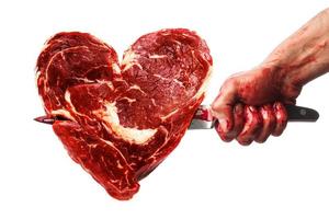 Male hand with bloody knife stabbed into the meat in shape of heart photo